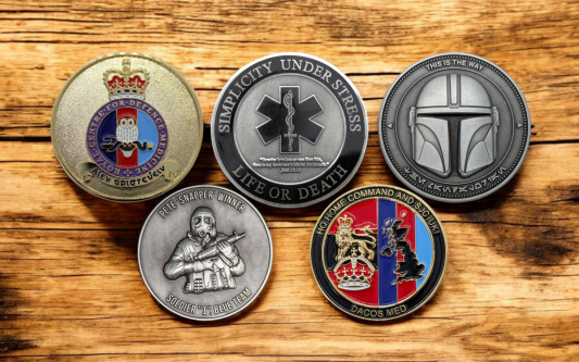 A collection of five challenge coins for military groups, emergency services, and for collecting.